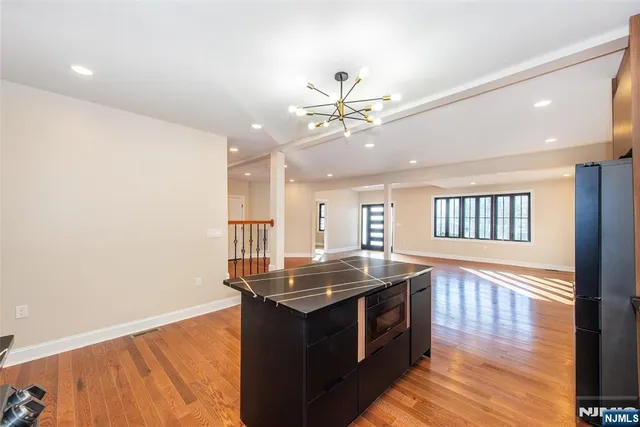a large kitchen with kitchen island a sink wooden floor and stainless steel appliances
