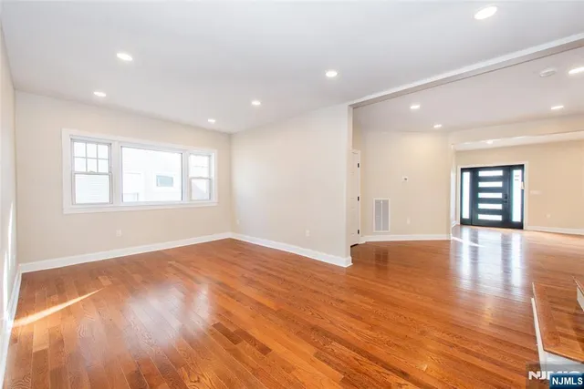 a view of an empty room with wooden floor and window