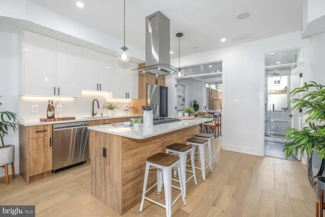 a kitchen with stainless steel appliances kitchen island granite countertop a refrigerator a sink dishwasher and a stove with wooden floor