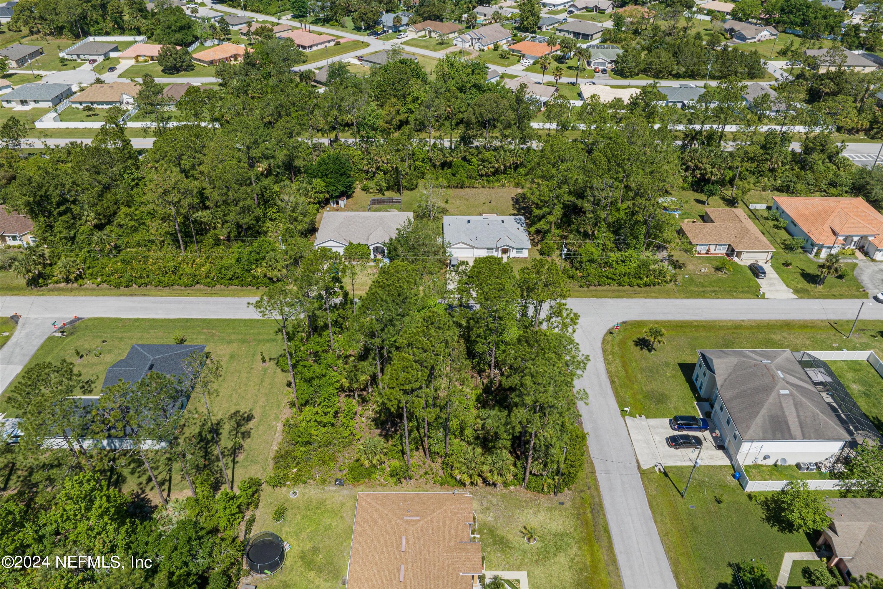 an aerial view of a residential houses with outdoor space and trees all around