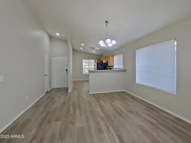 an empty room with kitchen view and wooden floor