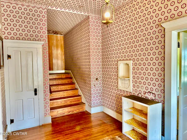 a view of a hallway with wooden floor and staircase
