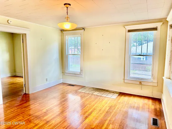 a view of an empty room with wooden floor and a window