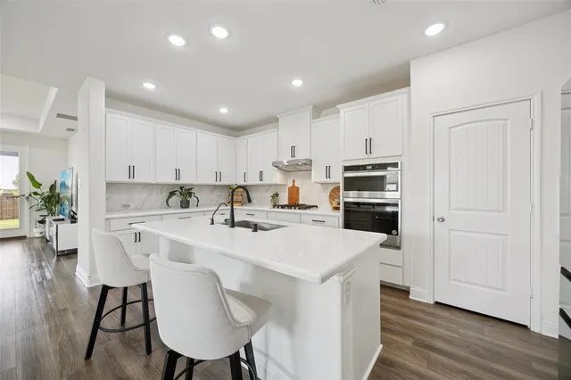 a kitchen with kitchen island a white counter top space a sink appliances and cabinets