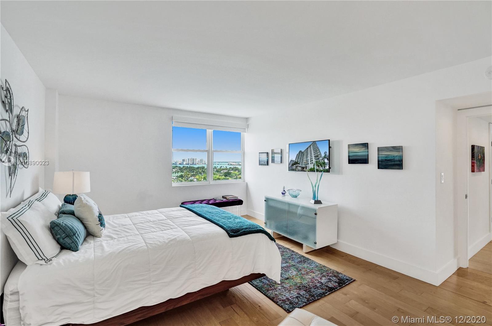 5750 Collins Avenue, Unit 15F Miami Beach, FL 33140 - Photo 34 of 65 a bedroom with a bed wooden floor and cabinet