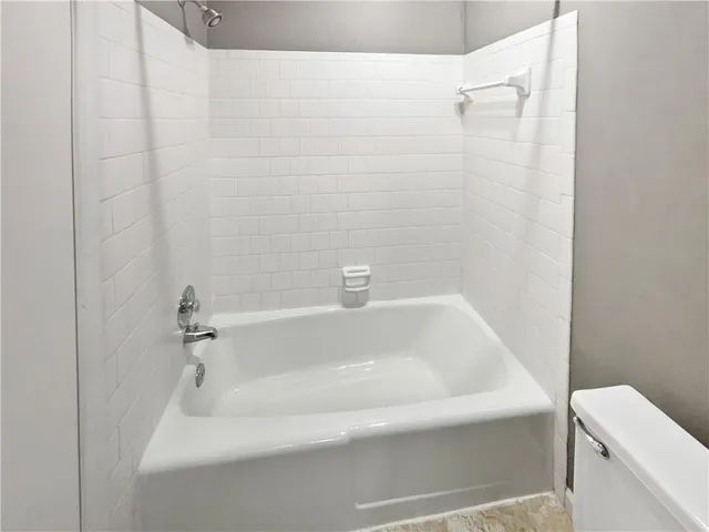 a white bath tub sitting next to a white toilet and a shower