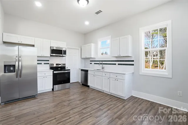 a kitchen with granite countertop white cabinets and stainless steel appliances