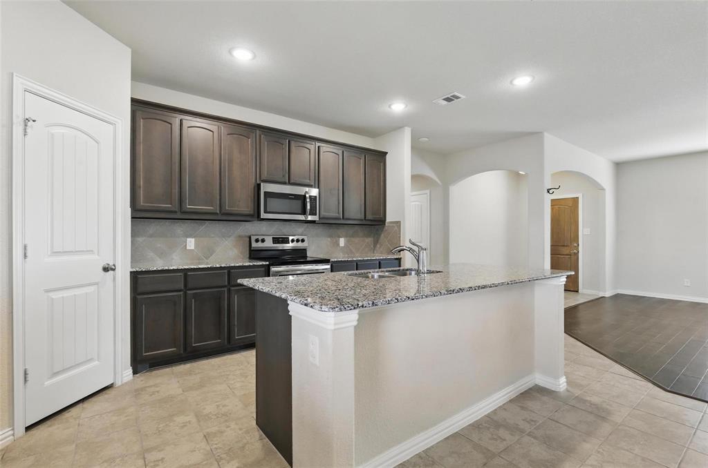 240 Springwood Ranch Loop Springtown, TX 76082 - Photo 7 of 27 a kitchen with stainless steel appliances granite countertop a stove a sink and a refrigerator with wooden floor