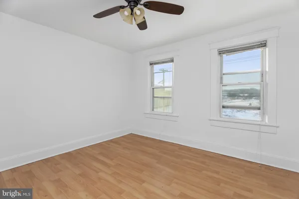 a view of empty room with wooden floor and fan