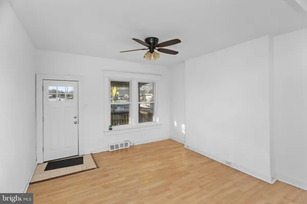 an empty room with chandelier fan and windows