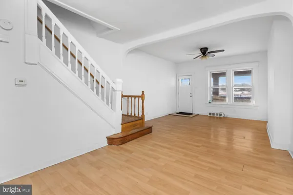 a view of an empty room with wooden floor and a ceiling fan