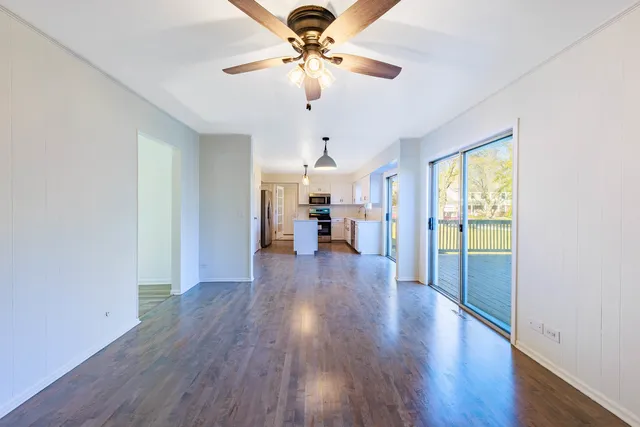 a view of a livingroom with wooden floor a ceiling fan and windows