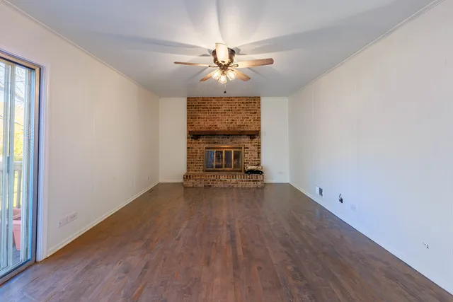 an empty room with wooden floor chandelier fan and windows
