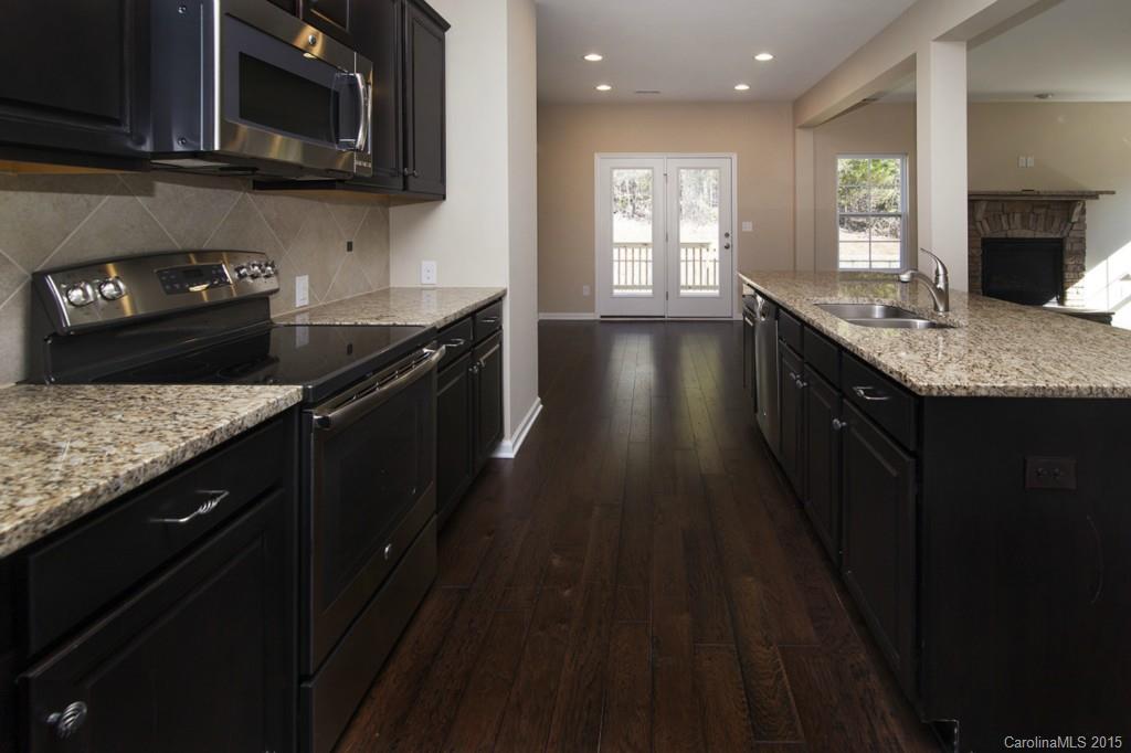 710 Old Cove Road, Unit 42 Tega Cay, SC 29708 - Photo 9 of 23 a kitchen with granite countertop stainless steel appliances a sink stove top oven and wooden floor