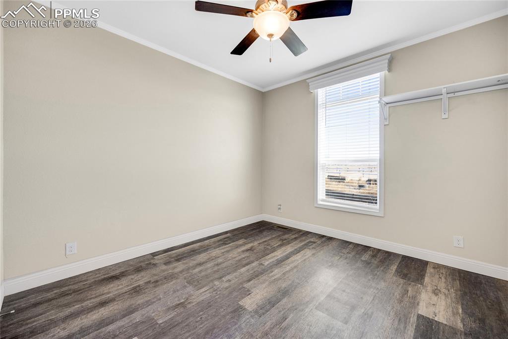 7880 J D Johnson Road Peyton, CO 80831 - Photo 43 of 50 Empty room featuring crown molding, dark wood-style floors, and ceiling fan