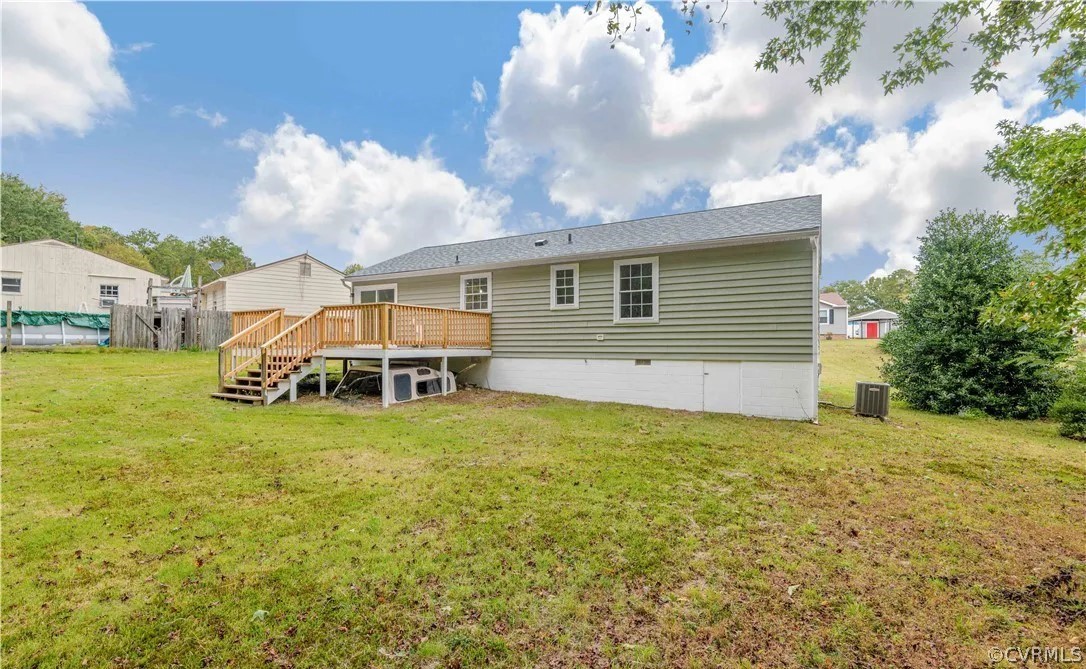 Back of house with central AC unit, a yard, and a