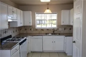 a kitchen with granite countertop white cabinets and window