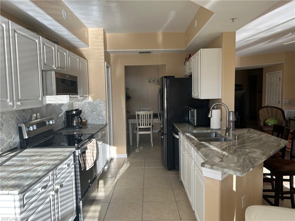 1390 Tiffany Lane, Unit 2302 Naples, FL 34105 - Photo 11 of 37 a kitchen with a sink stove and cabinets