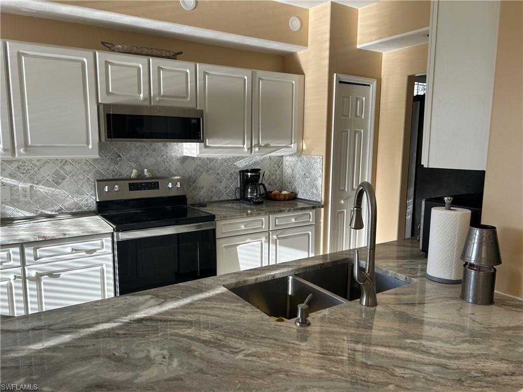 1390 Tiffany Lane, Unit 2302 Naples, FL 34105 - Photo 9 of 37 a kitchen with stainless steel appliances granite countertop a stove a sink and a microwave
