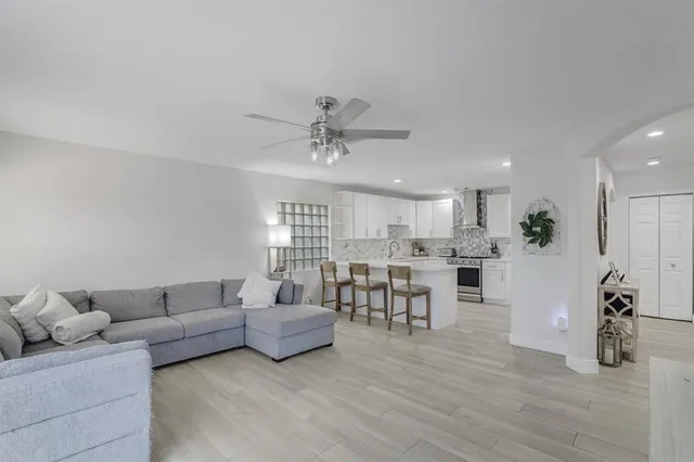 a living room with furniture with kitchen view and a wooden floor