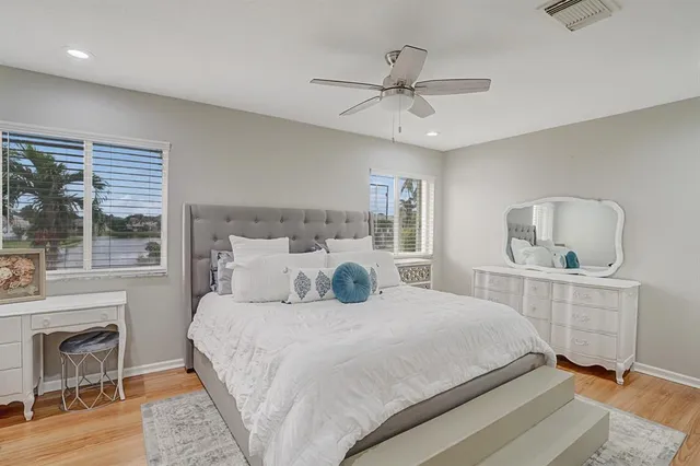 a bedroom with a bed a ceiling fan and a large window