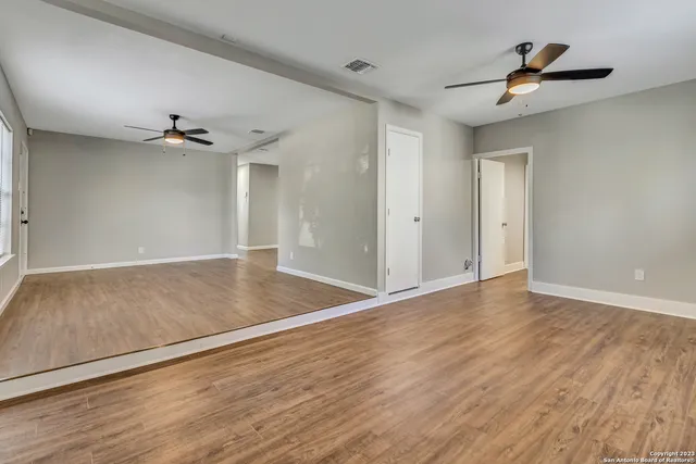 a view of empty room with wooden floor and fan