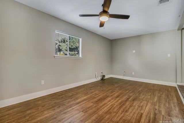 an empty room with wooden floor and windows