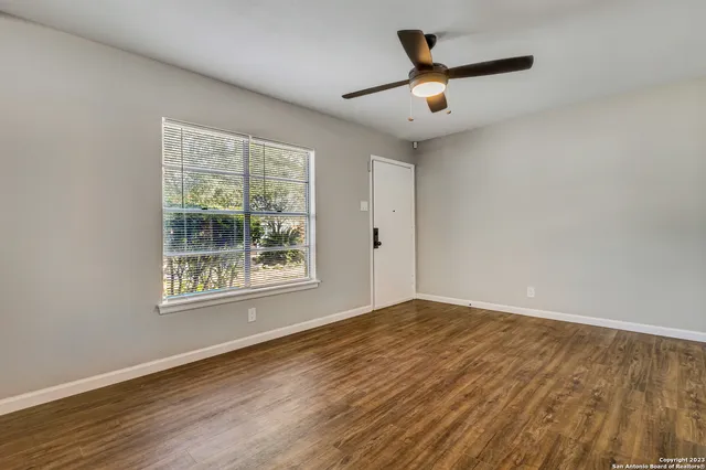 a view of an empty room with wooden floor and a window