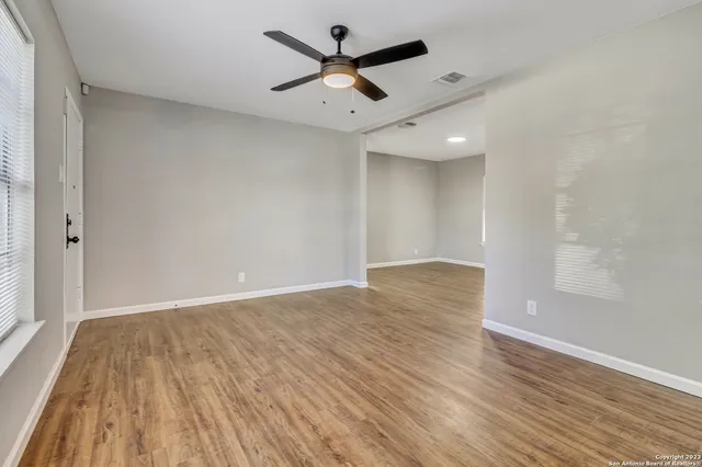 an empty room with wooden floor and windows