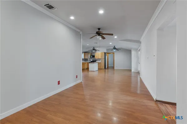 an empty room with wooden floor and a hallway