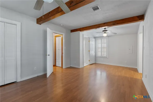 a view of an empty room with wooden floor and a window