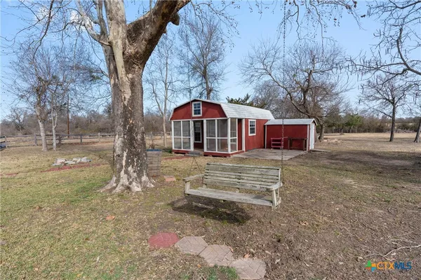a view of a house with a yard and large tree