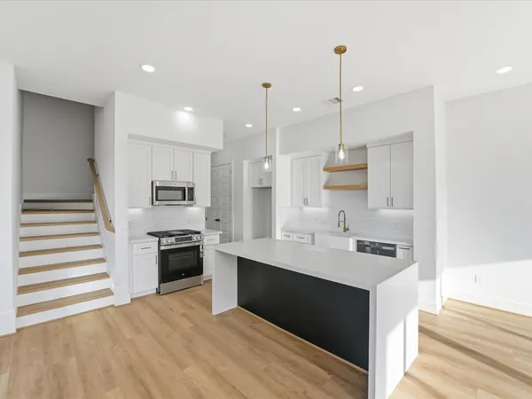 a kitchen with stainless steel appliances kitchen island granite countertop a sink stove and refrigerator