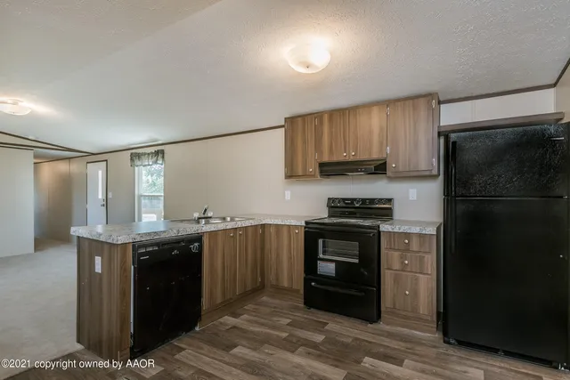 a kitchen with stainless steel appliances granite countertop a stove a refrigerator and a sink with wooden cabinets