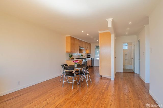 a kitchen with stainless steel appliances a stove a sink a microwave a stove and white cabinets with wooden floor