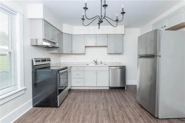 a kitchen with white cabinets stainless steel appliances and wooden floor