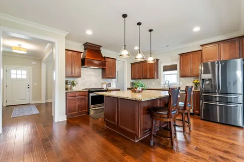 a kitchen with stainless steel appliances granite countertop a sink a stove a refrigerator and island with wooden floor