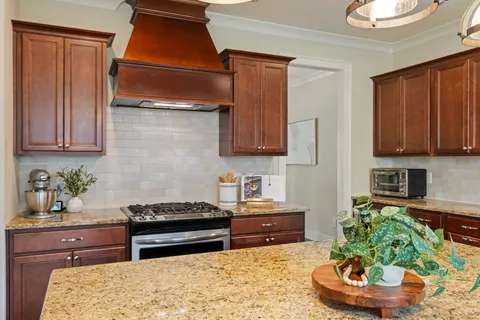 a kitchen with stainless steel appliances granite countertop a refrigerator a stove a kitchen island a dining table and chairs with wooden floor