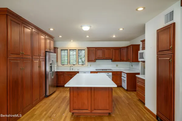 a kitchen with stainless steel appliances granite countertop a refrigerator a sink dishwasher and wooden cabinets with wooden floor