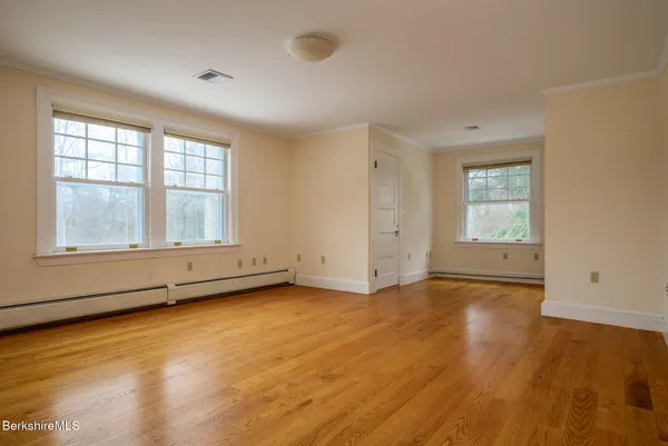 an empty room with wooden floor and windows