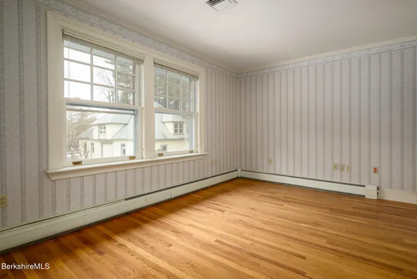 an empty room with wooden floor and windows