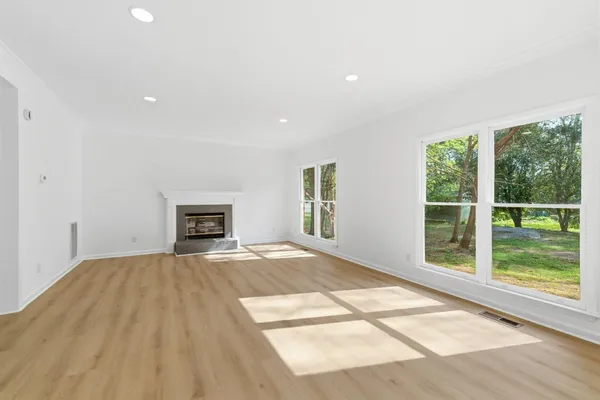 a view of an empty room with a window and wooden floor