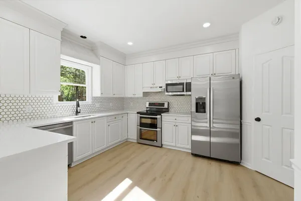 a kitchen with white cabinets stainless steel appliances and window