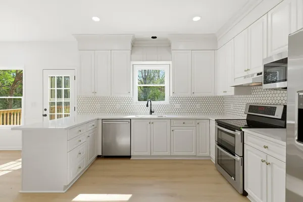 a kitchen with white cabinets appliances a sink and a window
