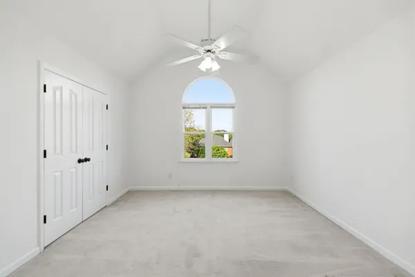 an empty room with a window and a ceiling fan