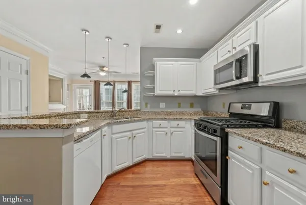 a kitchen with stainless steel appliances granite countertop a refrigerator a stove top oven a sink and a refrigerator