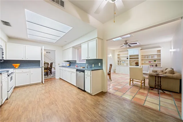 a kitchen with stainless steel appliances kitchen island wooden floors and white cabinets