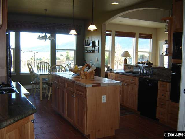 100 Antelope Valley Road Reno, NV 89506 - Photo 7 of 9 a kitchen with kitchen island granite countertop a stove a sink and a dining table with wooden floor
