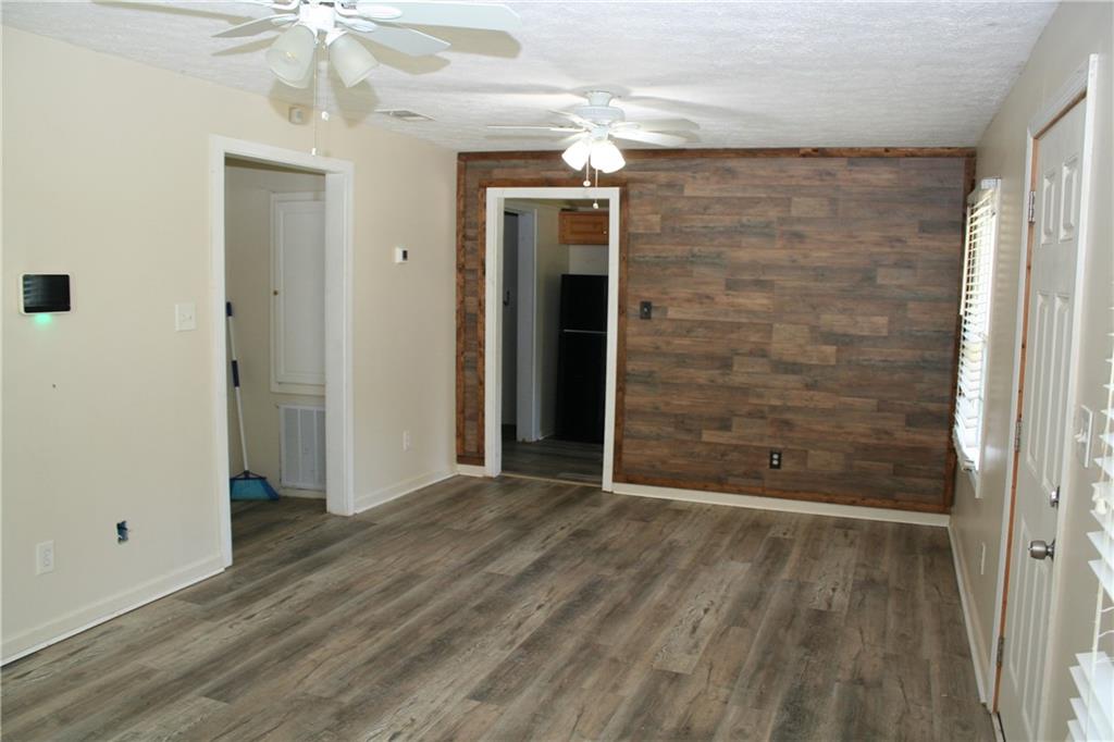 3735 South Seale Road Phenix City, AL 36869 - Photo 16 of 27 Living Room room with ceiling fan, LVP finished floors, a textured ceiling, and wood walls