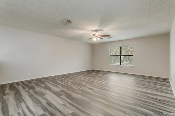 a view of an empty room with a window and wooden floor